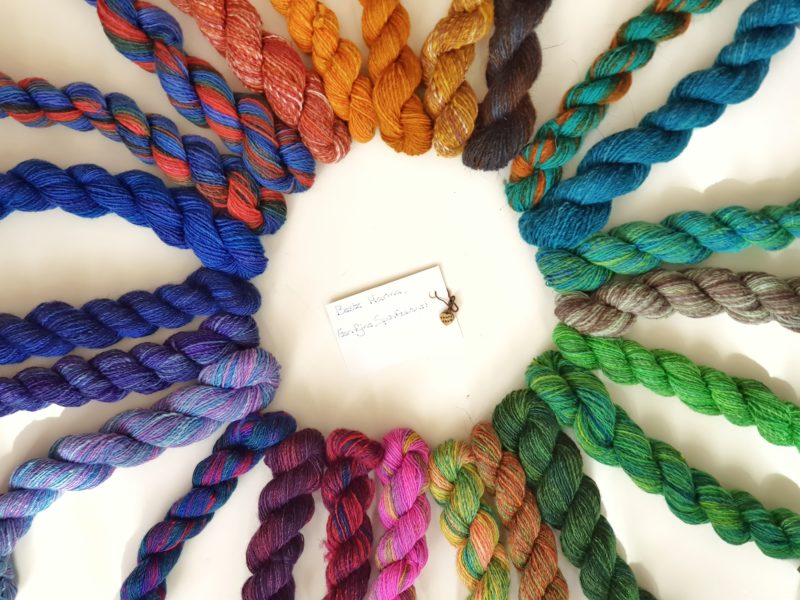24 mini skeins of yarn in all colours of the rainbow, arranged in a circle