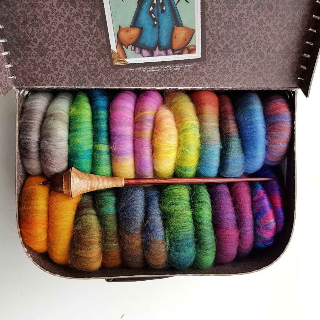 A small suitcase filled with colourful rolags.